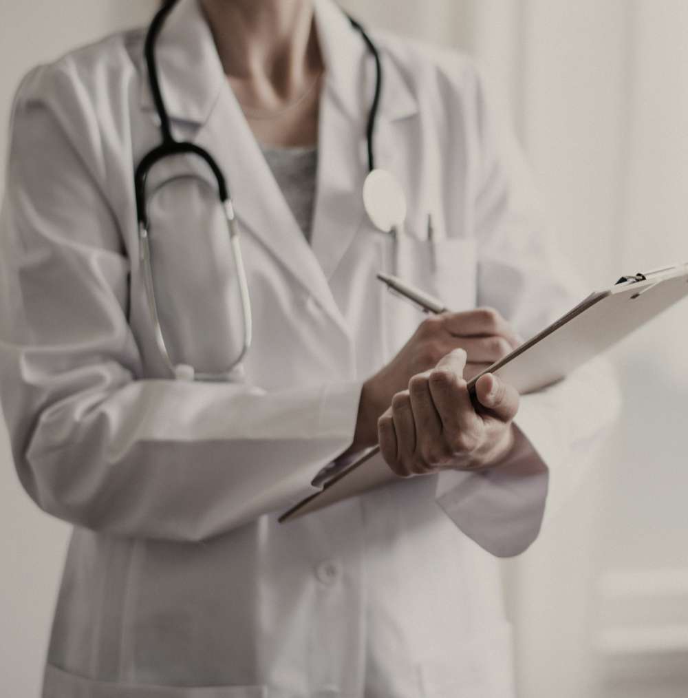 A nurse is holding a clipboard while inscribing something on it.
